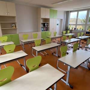 Blick in einen renovierten Klassenraum mit Tischen, Stühlen und Schränken