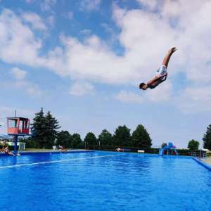 Schwimmbecken mit einer vom Sprungturm springenden Person